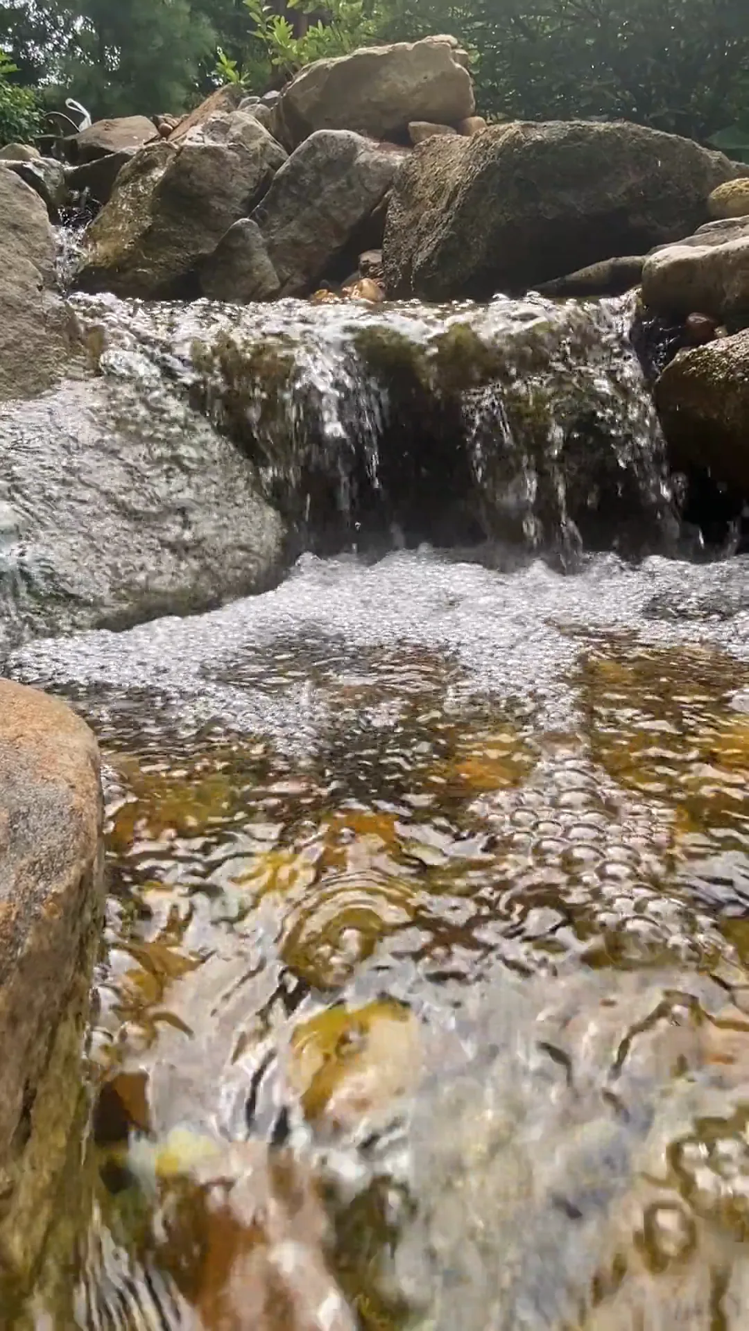 Water tumbling down a stacked stone waterfall, with its sound