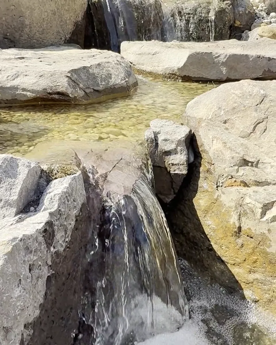 A waterfall pouring over large boulders into a pool