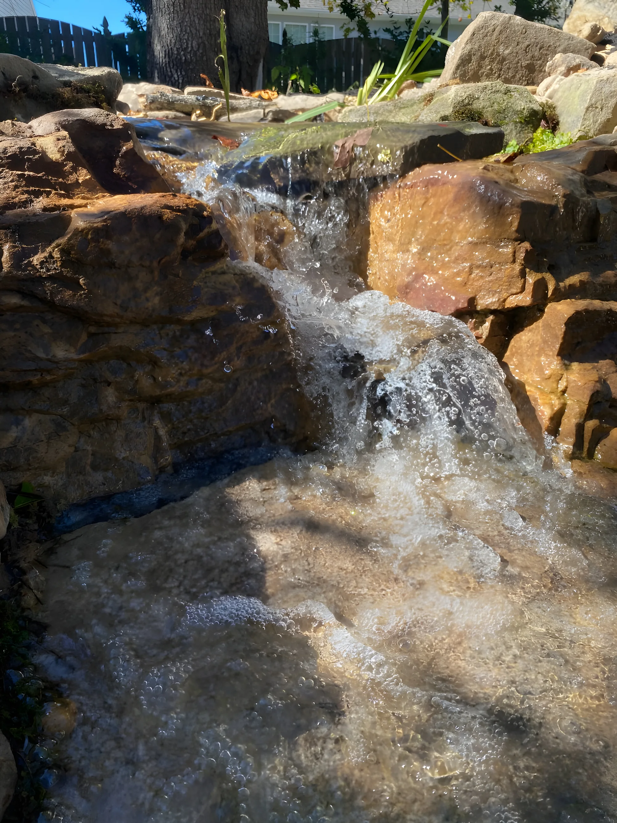 Water sliding down a sloped slab of stone into a pebble stream